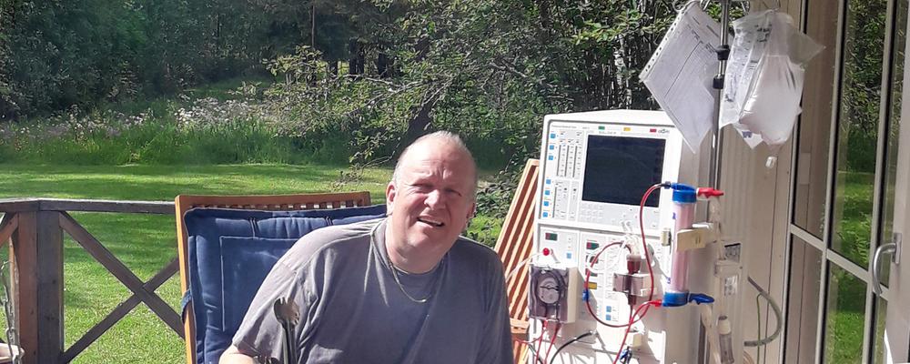 en man sitter i en trädgård med en dialysmaskin