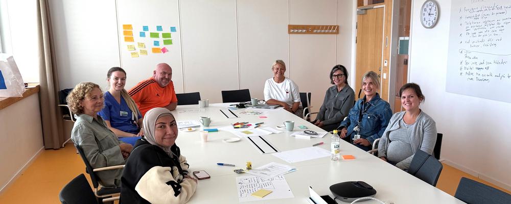 åtta personer runt ett bord i ett mötesrum som har workshop 